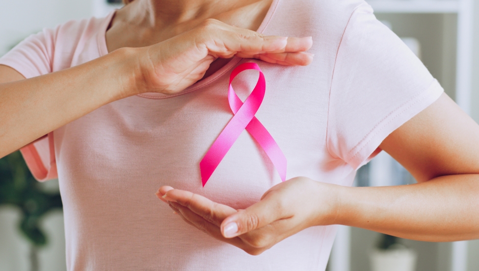 Asian woman show pink ribbon as sign of October Breast Cancer Awareness month