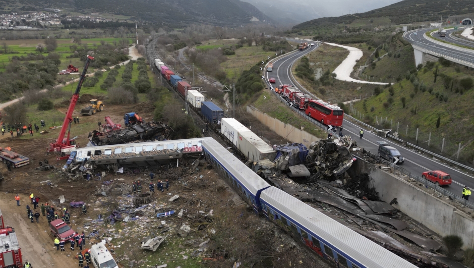 A crane, firefighters and rescuers operate after a collision in Tempe near Larissa city, Greece, Wednesday, March 1, 2023. A train carrying hundreds of passengers has collided with an oncoming freight train in northern Greece, killing and injuring dozens passengers. (AP Photo/Vaggelis Kousioras)