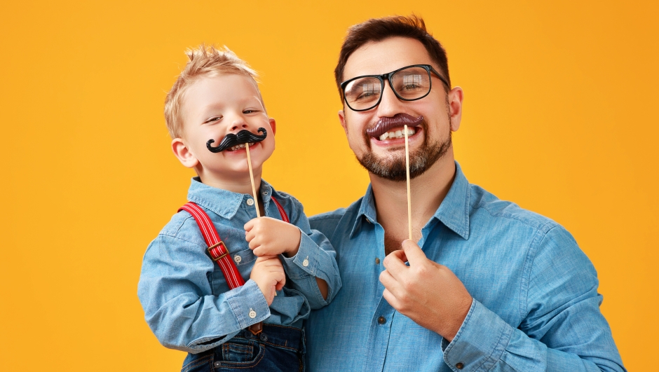 happy father's day! funny dad and son with mustache fooling around on colored yellow background