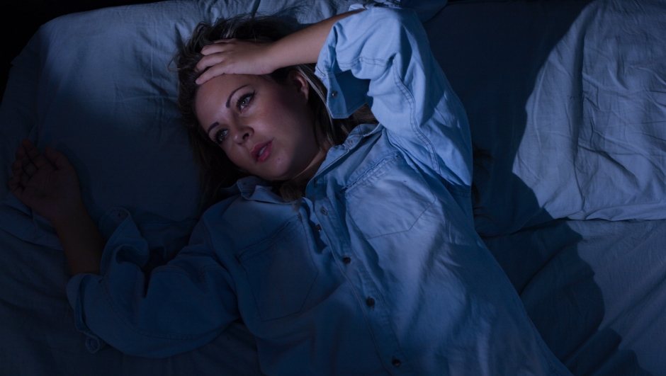 Sleep disorder, insomnia. Young blonde woman lying on the bed awake