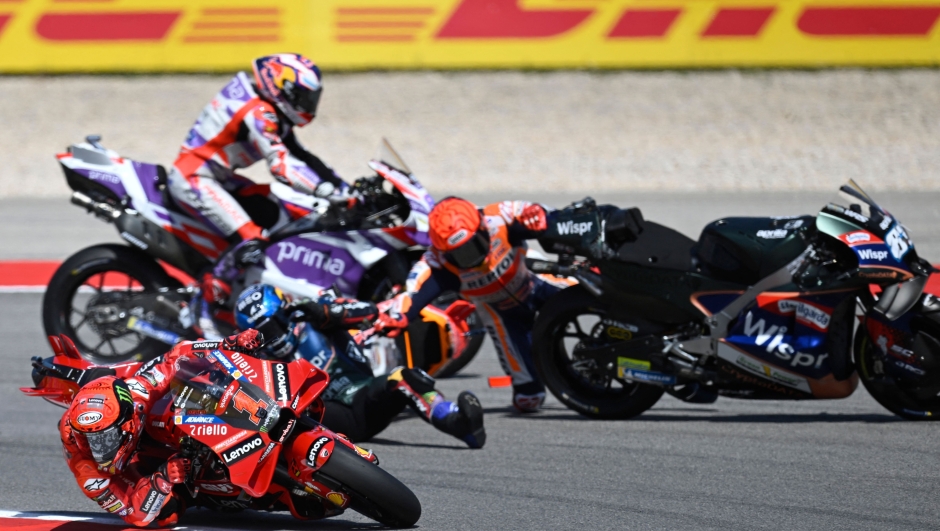 Honda Spanish rider Marc Marquez (R) crashes with Aprilia Portuguese rider Miguel Oliveira as Ducati Italian rider Francesco Bagnaia (L BOTTOM) rides past during the MotoGP race of the Portuguese Grand Prix at the Algarve International Circuit in Portimao, on March 26, 2023. (Photo by PATRICIA DE MELO MOREIRA / AFP)
