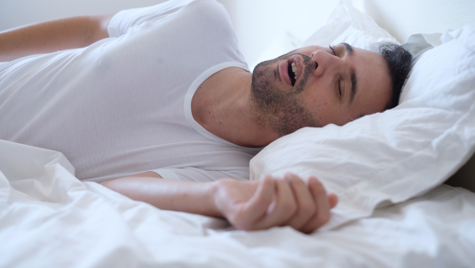 Man snoring because of sleep apnea lying in the bed