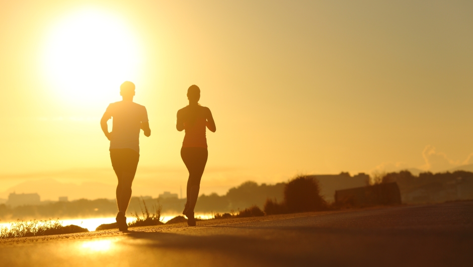 Couple practicing sport running at sunset on the road