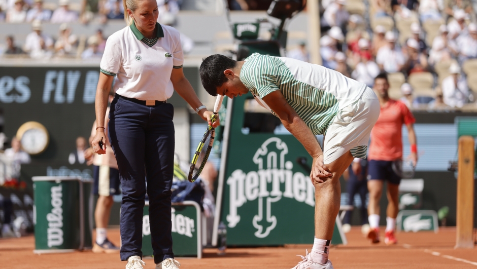 Spain's Carlos Alcaraz, right, speaks with chair umpire Aurelie Tourte of France as he reacts with pain at the end of the third game of the third set during his semifinal match of the French Open tennis tournament against Serbia's Novak Djokovic at the Roland Garros stadium in Paris, Friday, June 9, 2023. (AP Photo/Jean-Francois Badias)