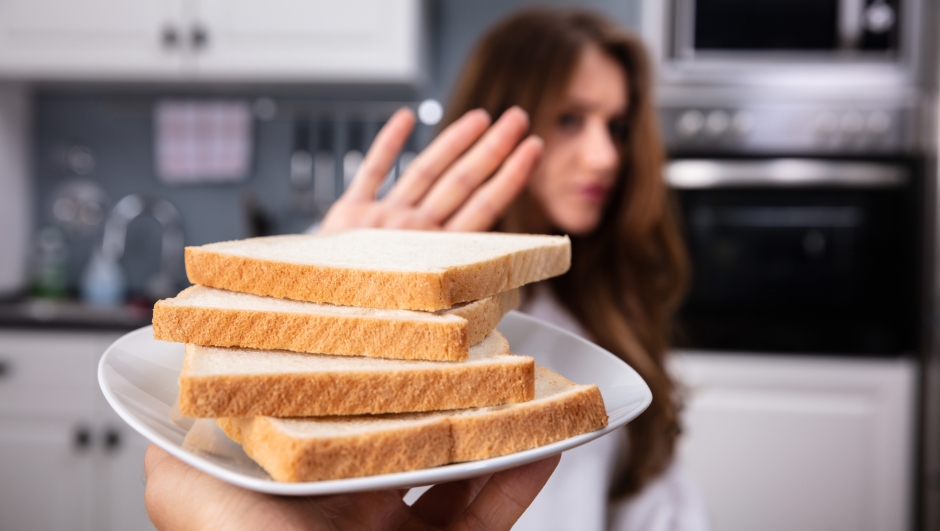 Young Woman Refusing Bread Slice On Plate At Home