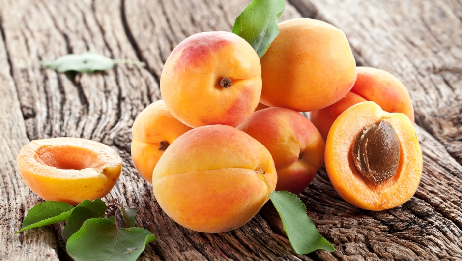 Apricots with leaves on the old wooden table.