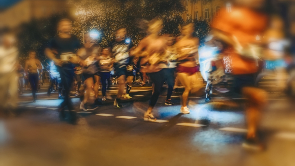 Large group of running athletes on street, night city marathon, blur effect, unrecognizable peole. Sport, fitness, healthy lifestyle concept. Abstract background