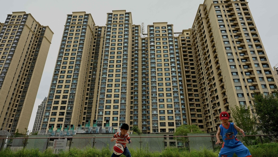 (FILES) Children play basketball in front of a housing complex by Chinese property developer Evergrande in Beijing on July 28, 2022. Embattled Chinese property giant Evergrande Group filed for bankruptcy protection in the United States on August 17, 2023, court documents showed, a measure that protects its US assets while it attempts to restructure. (Photo by NOEL CELIS / AFP)