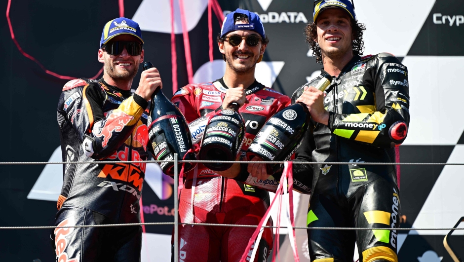 (L-R) Red Bull KTM Factory Racing South African rider Brad Binder, Ducati Lenovo Team Italian rider Francesco Bagnaia and Mooney VR46 Racing Team Italian rider Marco Bezzecchi celebrate on the podium their second, first and third places respectively after winning the MotoGP Austrian Grand Prix at the Red Bull Ring racetrack in Spielberg bei Knittelfeld, Austria, on August 20, 2023. (Photo by Jure Makovec / AFP)