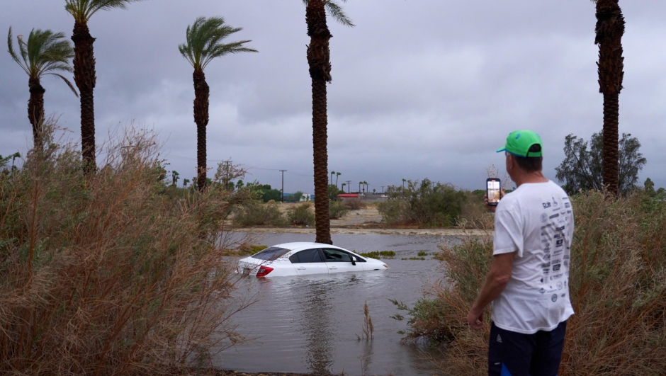 epa10811214 A person takes a photo of a car submerged in flooded water as Tropical Storm Hilary arrives in Cathedral City, California, USA, 20 August 2023. Southern California is under a tropical storm warning for the first time in history as Hilary makes landfall. The last time a tropical storm made landfall in Southern California was 15 September 1939, according to the National Weather Service.  EPA/ALLISON DINNER