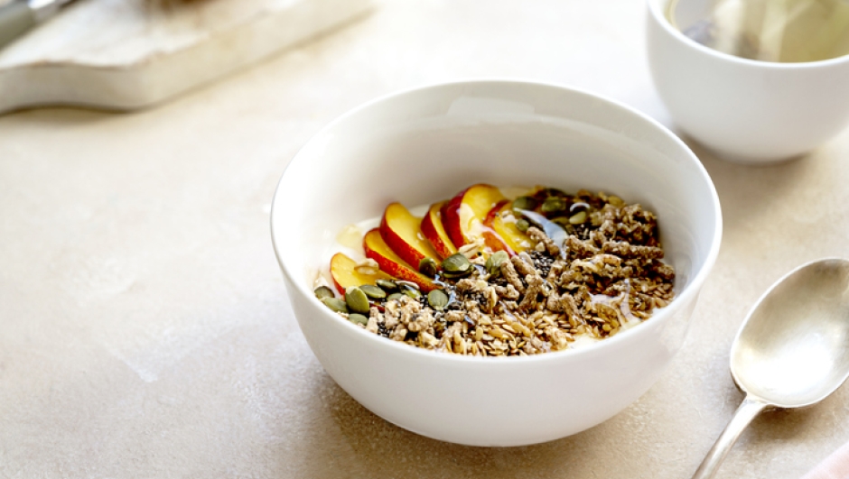 Healthy breakfast. Granola with peach fruit, nuts, chia seeds, pumpkin seeds and milk in a bowl, food photography