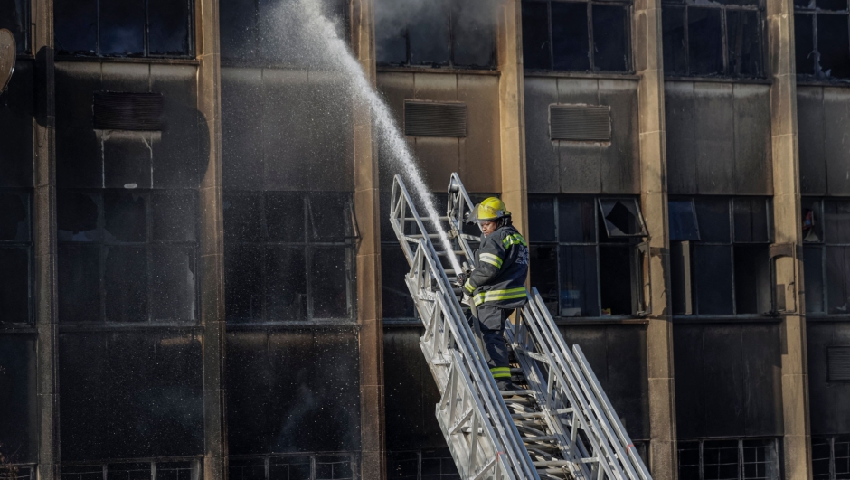 EDITORS NOTE: Graphic content / TOPSHOT - A firefighter extinguishes the fire at a building in Johannesburg on August 31, 2023. At least 20 people have died and more than 40 were injured in a fire that engulfed a five-storey building in central Johannesburg on August 31, 2023, the South African city's emergency services said. (Photo by Michele Spatari / AFP)