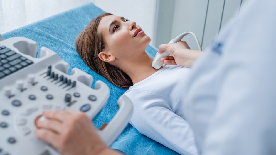 Woman getting her neck examined by doctor using ultrasound scanner at modern clinic