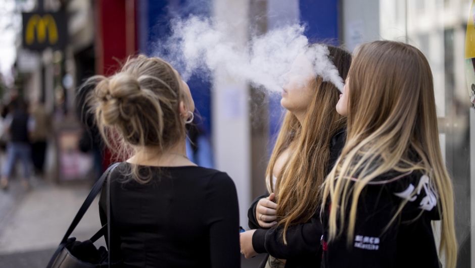 epa10663276 Young people use single-use vaping products in London, Britain, 30 May 2023. The UK government has announced it is cracking down on retailers providing free vape samples to children. The government's new proposals include rules on fines for shops selling illicit vapes to children under 18-years-old.  EPA/TOLGA AKMEN