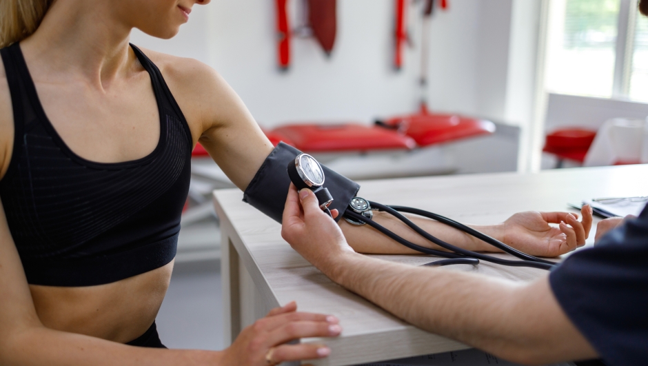 Close-up view of a physiotherapist doctor and sports woman whose blood pressure is measured in a rehabilitation gym