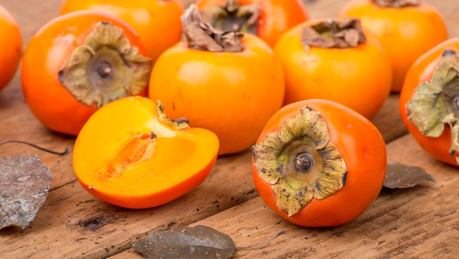 Fresh ripe persimmon on a rough, wooden, rustic table
