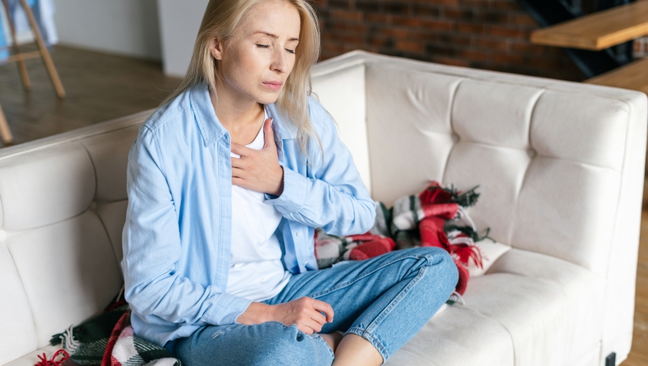 Exhausted, worried woman feeling pain ache, touching her chest, having heart attack or disease symptom, suffers from heartache sitting at home alone