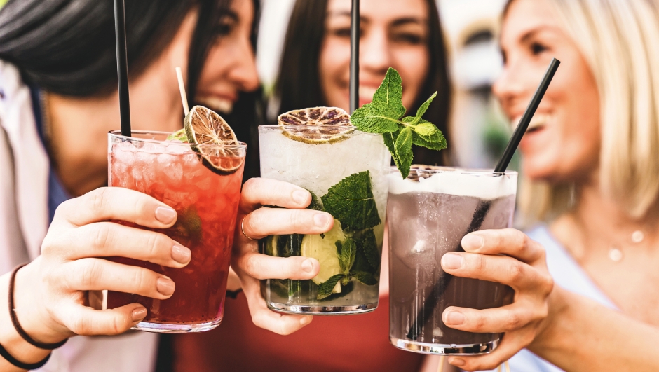 Group of happy friends toasting and drinking fancy cocktails at bar terrace-Three Young girls drink mojito and clinking glass together at pub enjoying happy hour at summer party- Life Style concept