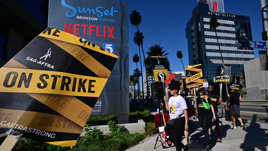 (FILES) SAG-AFTRA members picket outside of Netflix's building on day 99 of their strike against the Hollywood studios in Hollywood, California on October 20, 2023. Hollywood actors and studios reached a tentative deal November 8, 2023 to end a months-long strike that has crippled the entertainment industry, delayed hundreds of popular shows and films, and cost billions to the US economy. The Screen Actors Guild (SAG-AFTRA) called off its 118-day strike from midnight (0800 GMT Thursday) after finally reaching an agreement with the likes of Disney and Netflix for a new contract including higher pay, and protections against the use of artificial intelligence. (Photo by Frederic J. BROWN / AFP)