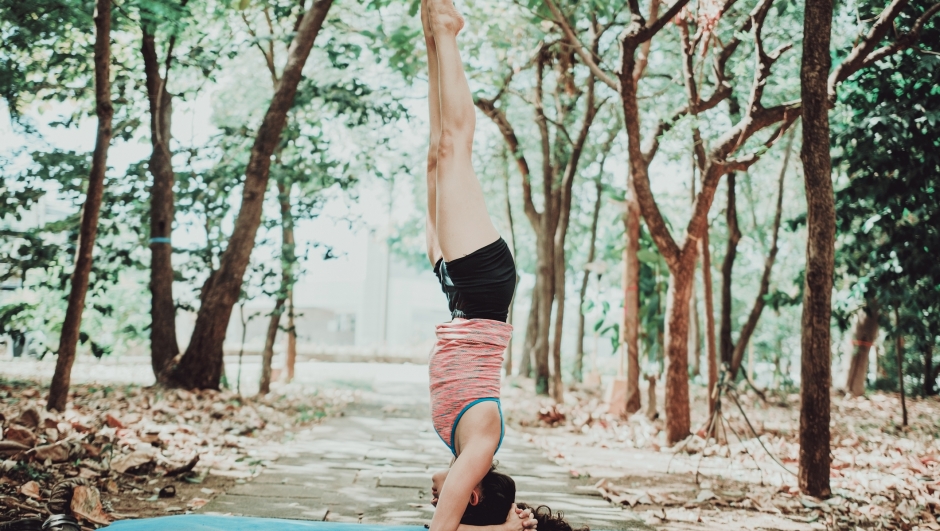 Young woman doing headstand yoga outdoors. Spiritual girl practicing yoga sirshasana outdoors.