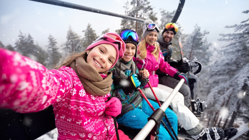 Happy family with children in cable car climb to ski terrain