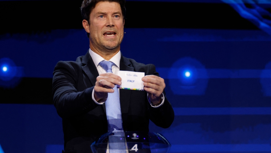 Danish Former footballer Brian Laudrup holds up a slip of paper after drawing Italy from the pot during the final draw for the UEFA Euro 2024 European Championship football competition in Hamburg, northern Germany on December 2, 2023. (Photo by Odd ANDERSEN / AFP)