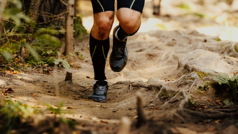legs men runner in compression socks running on tree roots