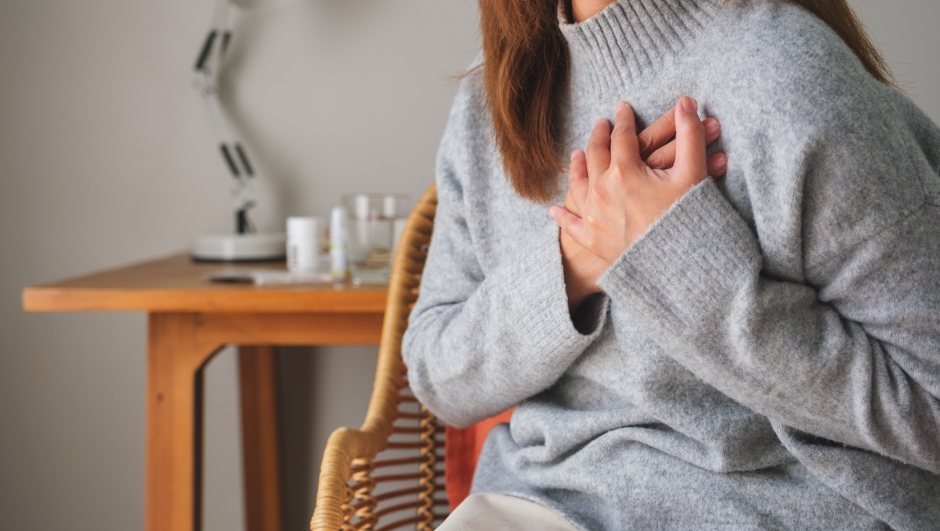 Closeup image of a woman with hands on chest, sudden heart attack, suffering from chest pain