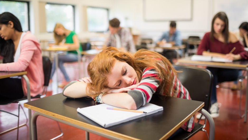 Blurred young college students sitting in the classroom with one asleep girl