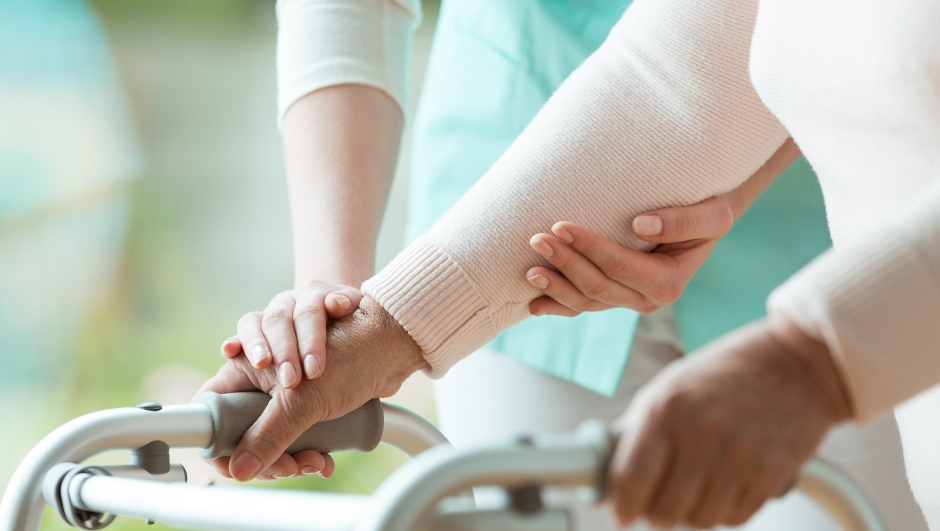 Close-up photo of patient's hands placed on metal walker