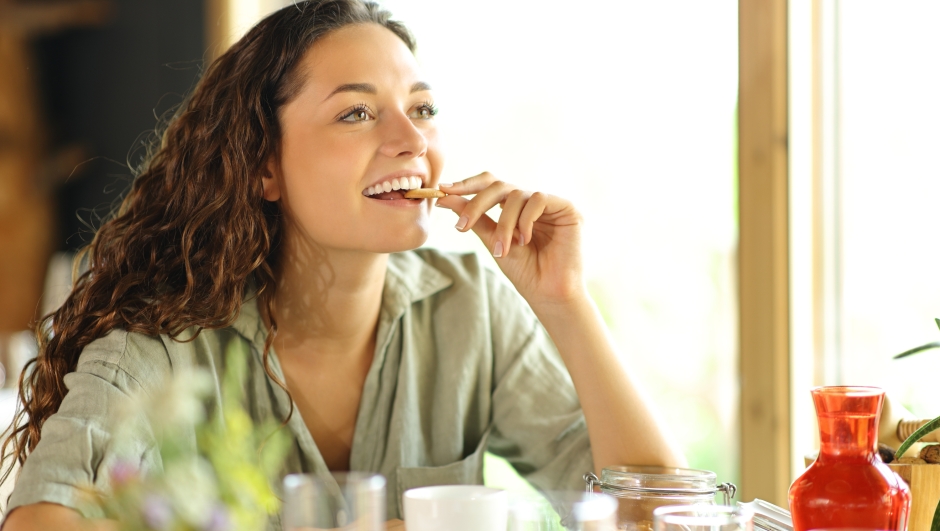 Happy woman eating cookie in a restaurant