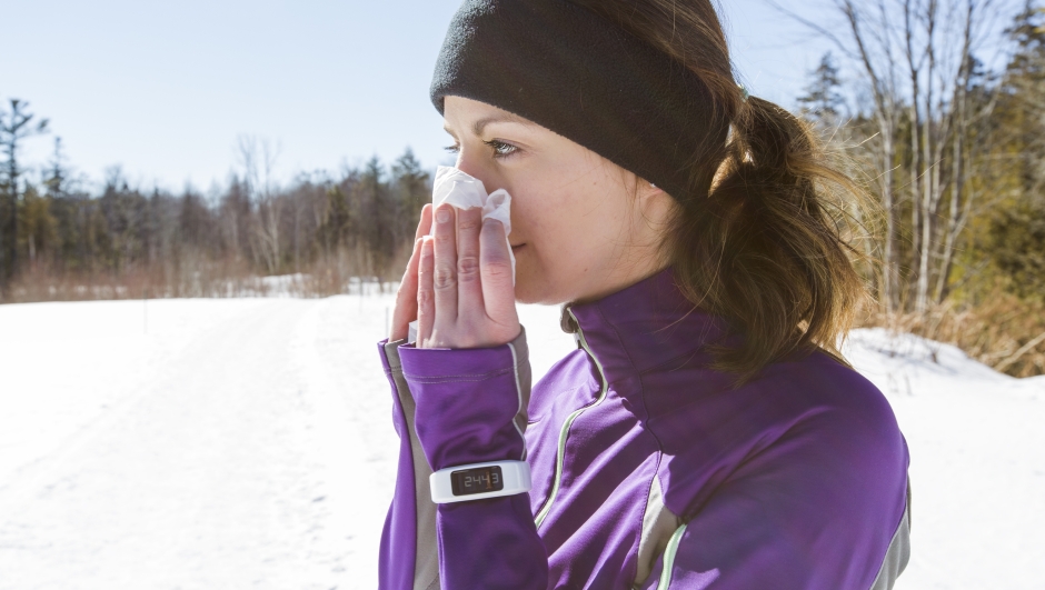 A Woman blowing her nose outside in the cold