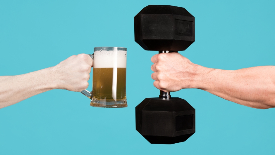 A muscular male hand holds out a heavy dumbbell towards a glass with beer in the other man s hand. Contrasting alcoholism with sports