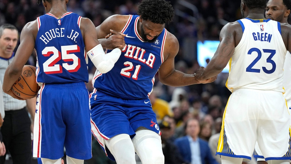 SAN FRANCISCO, CALIFORNIA - JANUARY 30: Joel Embiid #21 of the Philadelphia 76ers gets helped up from the floor by teammate Danuel House Jr. #25 and Draymond Green #23 of the Golden State Warriors during the second quarter at Chase Center on January 30, 2024 in San Francisco, California. NOTE TO USER: User expressly acknowledges and agrees that, by downloading and or using this photograph, User is consenting to the terms and conditions of the Getty Images License Agreement.   Thearon W. Henderson/Getty Images/AFP (Photo by Thearon W. Henderson / GETTY IMAGES NORTH AMERICA / Getty Images via AFP)