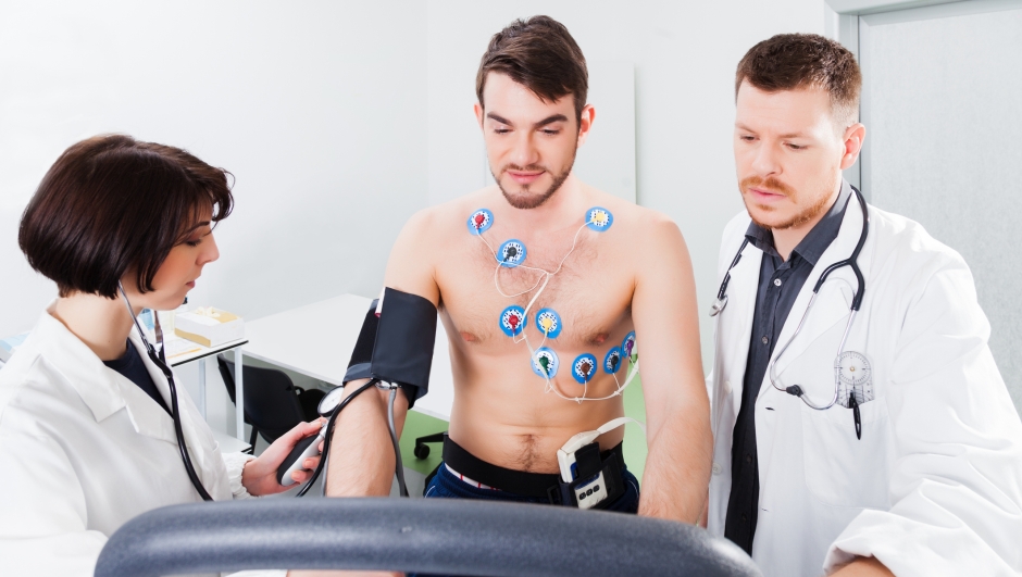 Athlete does a cardiac stress test in a medical study, monitored by the doctor and nurse