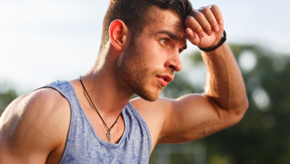 Closeup portrait of young muscular sweaty man after workout outside on sunny day
