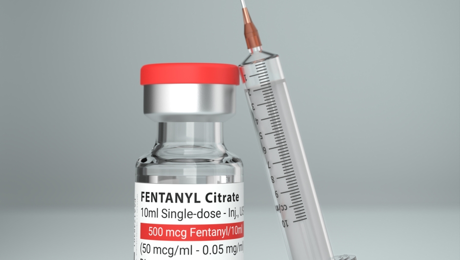 A vial of the Fentanyl drug used as an analgesic but also source of the opioid crisis. A syringe leaning against the vial.