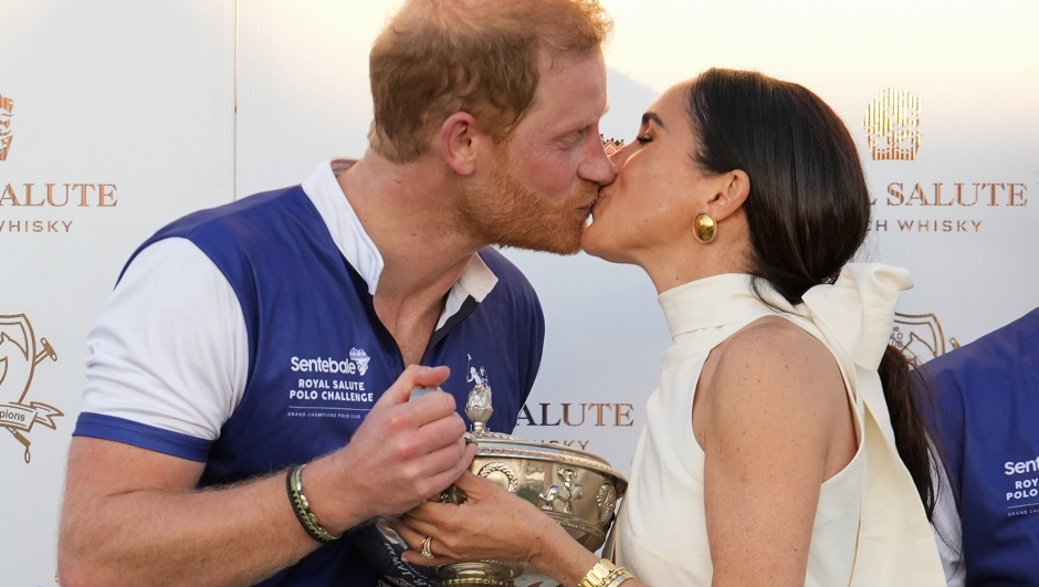 Britain's Prince Harry and wife Meghan Markle, Duchess of Sussex, kiss as she presents his polo team with the trophy for winning the 2024 Royal Salute Polo Challenge to Benefit Sentebale, Friday, April 12, 2024, in Wellington, Fla. His teammates are, from left, Dana Barnes, Adolfo Cambiaso, and Malcolm Borwick. (AP Photo/Rebecca Blackwell)