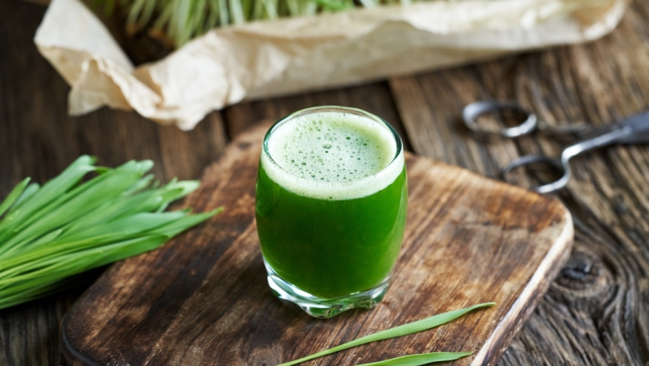 A glass of green juice made from fresh young barley grass
