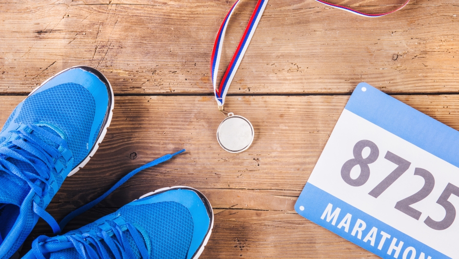 Pair of running shoes, medal and race number on a wooden floor background