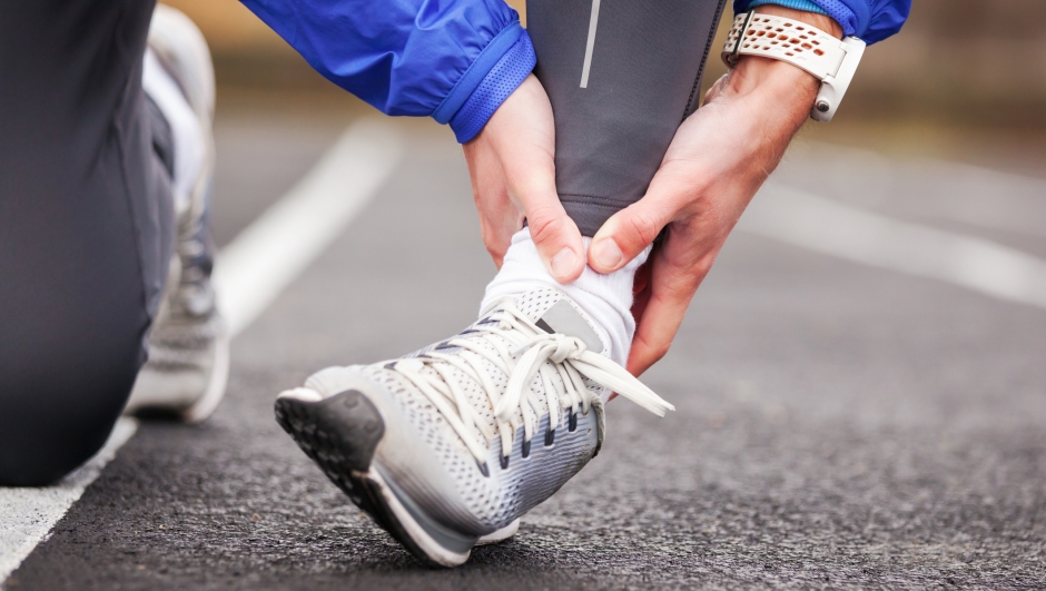 Cropped shot of a young man holding his ankle in pain while running.
