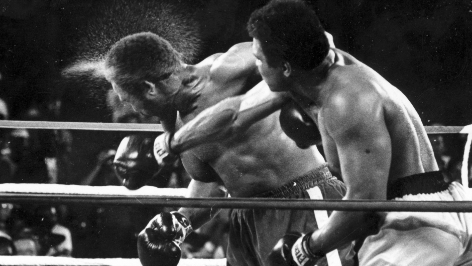 FILE - This is a Oct. 30, 1974,  file photo showing George Foreman taking a right to the head from challenger Muhammad Ali in the seventh round in the match dubbed Rumble in the Jungle in Kinshasa, Zaire. Ali, the magnificent heavyweight champion whose fast fists and irrepressible personality transcended sports and captivated the world, has died according to a statement released by his family Friday, June 3, 2016. He was 74. (AP Photo/Ed Kolenovsky, File)