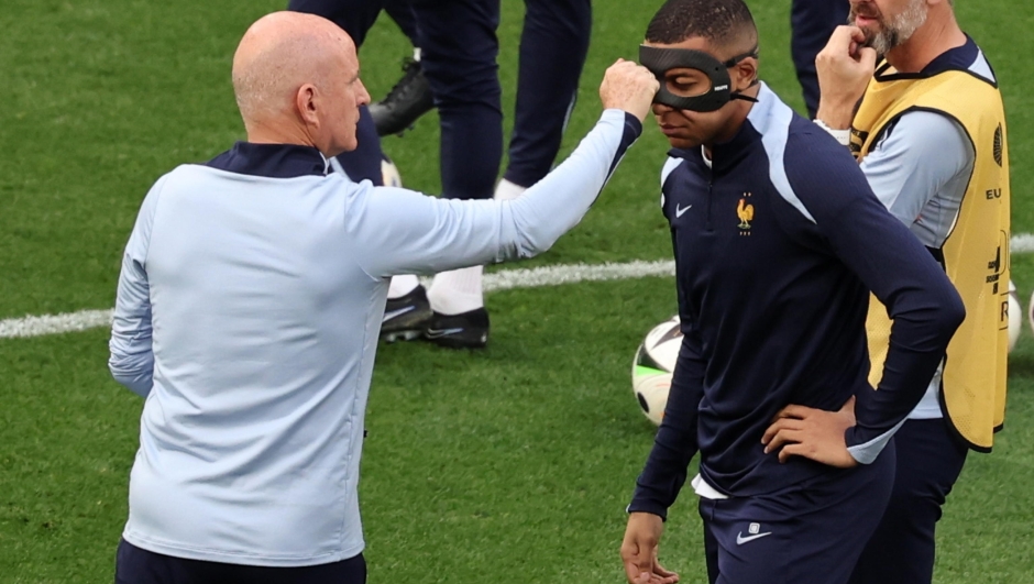epa11429029 Kylian Mbappe of France interacts with a member of France's team adjusting his mask ahead of the UEFA EURO 2024 Group D soccer match between the Netherlands and France, in Leipzig, Germany, 21 June 2024.  EPA/MOHAMED MESSARA