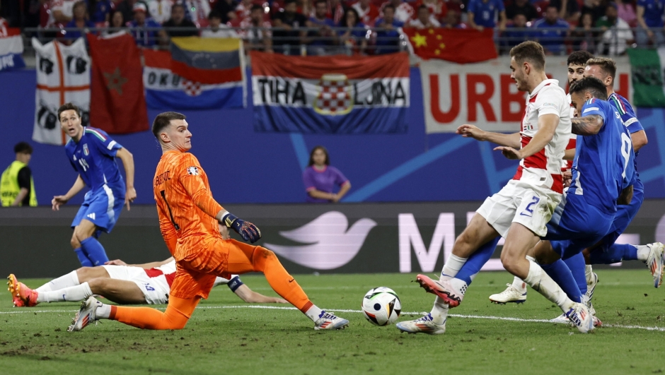 epa11435374 Goalkeeper Dominik Livakovic (L) of Croatia watches as his teammate Josip Stanisic (no.2) of Croatia and Gianluca Scamacca of Italy try to get to the ball during the UEFA EURO 2024 group B soccer match between Croatia and Italy, in Leipzig, Germany, 24 June 2024.  EPA/ROBERT GHEMENT