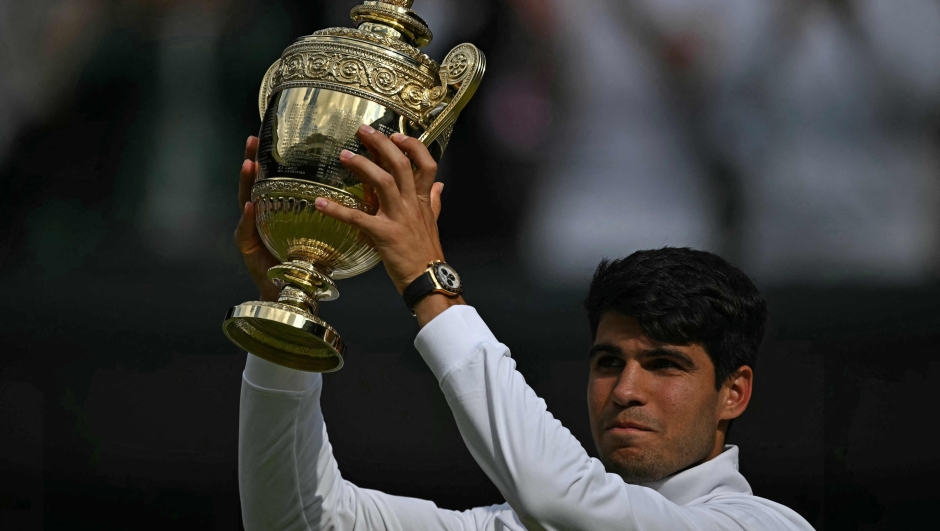 Spain's Carlos Alcaraz poses with the winner's trophy after beating Serbia's Novak Djokovic during their men's singles final tennis match on the fourteenth day of the 2024 Wimbledon Championships at The All England Lawn Tennis and Croquet Club in Wimbledon, southwest London, on July 14, 2024. Defending champion Alcaraz beat seven-time winner Novak Djokovic in a blockbuster final, with Alcaraz winning 6-2, 6-2,7-6. (Photo by Ben Stansall / AFP) / RESTRICTED TO EDITORIAL USE