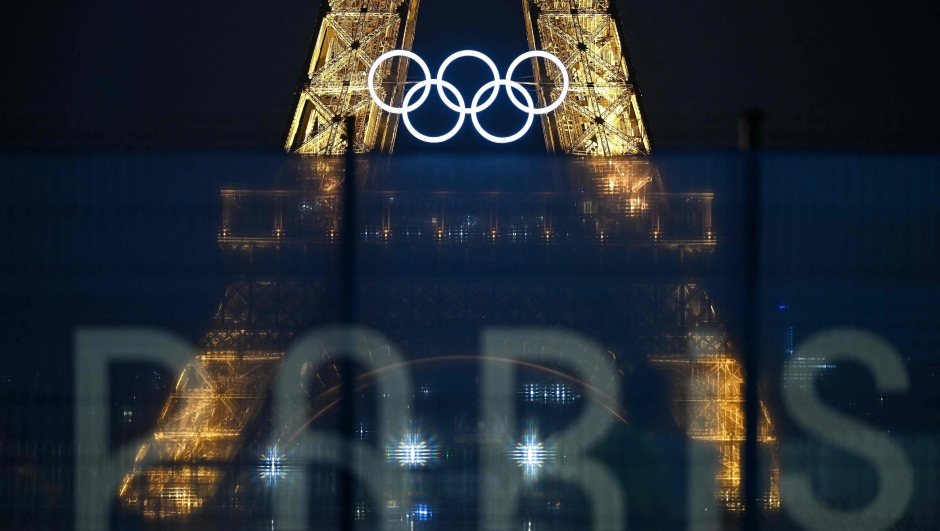 TOPSHOT - This photograph shows the Eiffel Tower bearing the Olympics rings, lit-up ahead of the Paris 2024 Olympic and Paralympic games, in Paris on July 20, 2024. (Photo by MANAN VATSYAYANA / AFP)