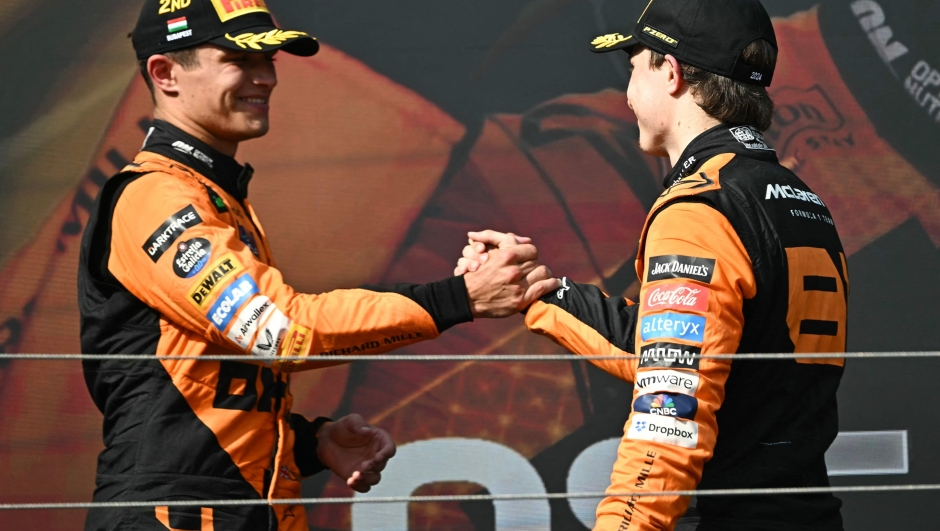 McLaren's Australian driver Oscar Piastri (R) is congratulated by McLaren's British driver Lando Norris on the podium after the Formula One Hungarian Grand Prix at the Hungaroring race track in Mogyorod near Budapest on July 21, 2024. (Photo by Attila KISBENEDEK / AFP)