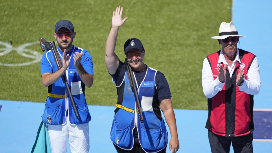Italy's Diana Bacosi, center, and teammate Gabriele Rossetti, left, react as they are introduced before the Skeet mixed team final at the 2024 Summer Olympics, Monday, Aug. 5, 2024, in Chateauroux, France. (AP Photo/Manish Swarup)