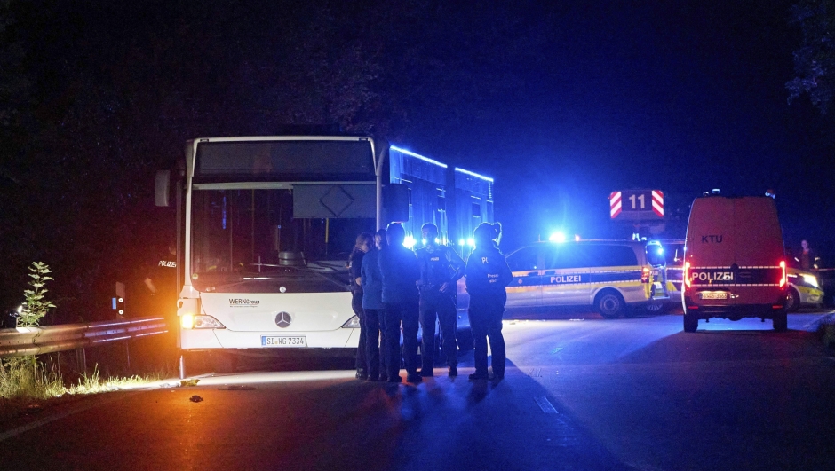 Police officers stand in front of a bus on a special route to a city festival in Siegen, Germany, Friday, Aug. 30, 2024, after a suspect allegedly attacked other passengers on the bus with a knife. (Sascha Ditscher/dpa via AP)