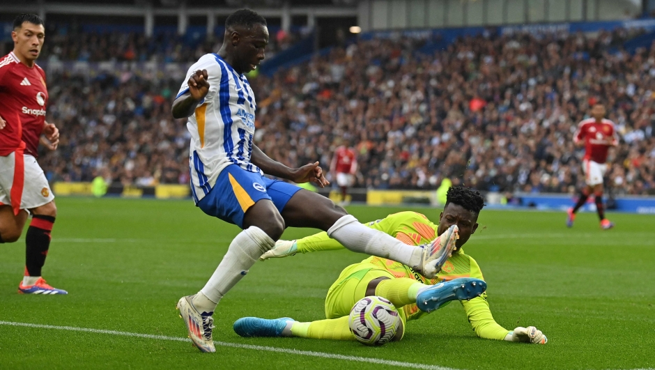 Manchester United's Cameroonian goalkeeper #24 Andre Onana saves from the feet of Brighton's Gambian midfielder #17 Yankuba Minteh during the English Premier League football match between Brighton and Hove Albion and Manchester United at the American Express Community Stadium in Brighton, southern England on August 24, 2024. (Photo by Glyn KIRK / AFP) / RESTRICTED TO EDITORIAL USE. No use with unauthorized audio, video, data, fixture lists, club/league logos or 'live' services. Online in-match use limited to 120 images. An additional 40 images may be used in extra time. No video emulation. Social media in-match use limited to 120 images. An additional 40 images may be used in extra time. No use in betting publications, games or single club/league/player publications. /